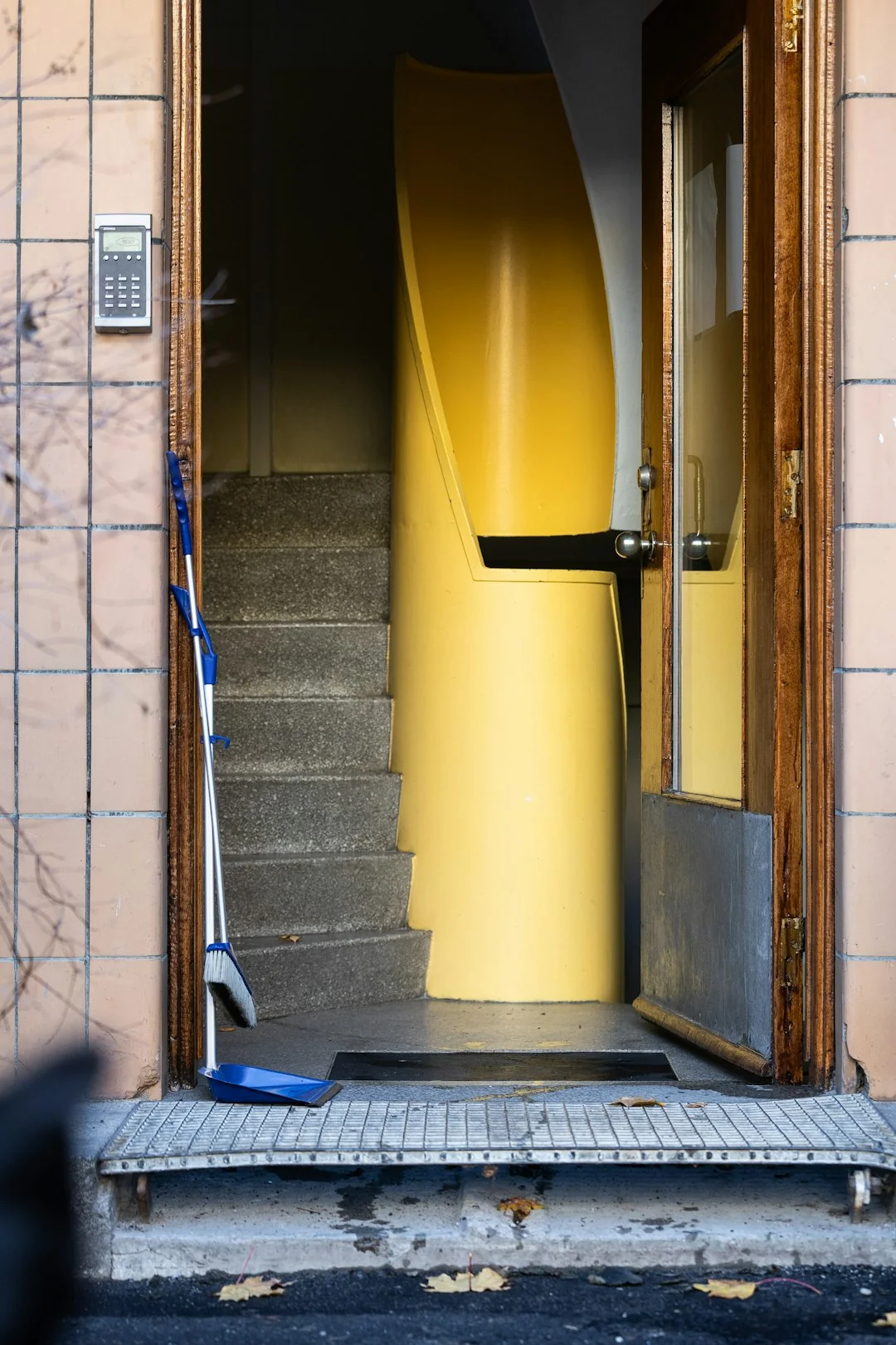 A professional cleaner in red coveralls vacuums a contemporary living room with a yellow vacuum cleaner.